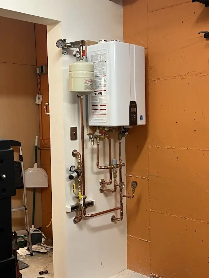 Plumbing technician inspecting water heater connections in Bon Air